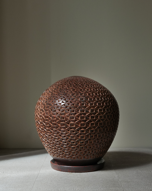 Agapanto: handmade Nicaraguan ceramic round brown vessel with a carved honeycomb pattern, on a wooden base