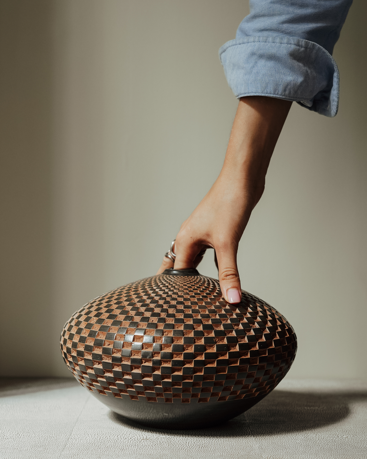 Concepción: handmade Nicaraguan ceramic wide, low vessel with a carved chequered pattern in terracotta and slate grey, steadied by a hand